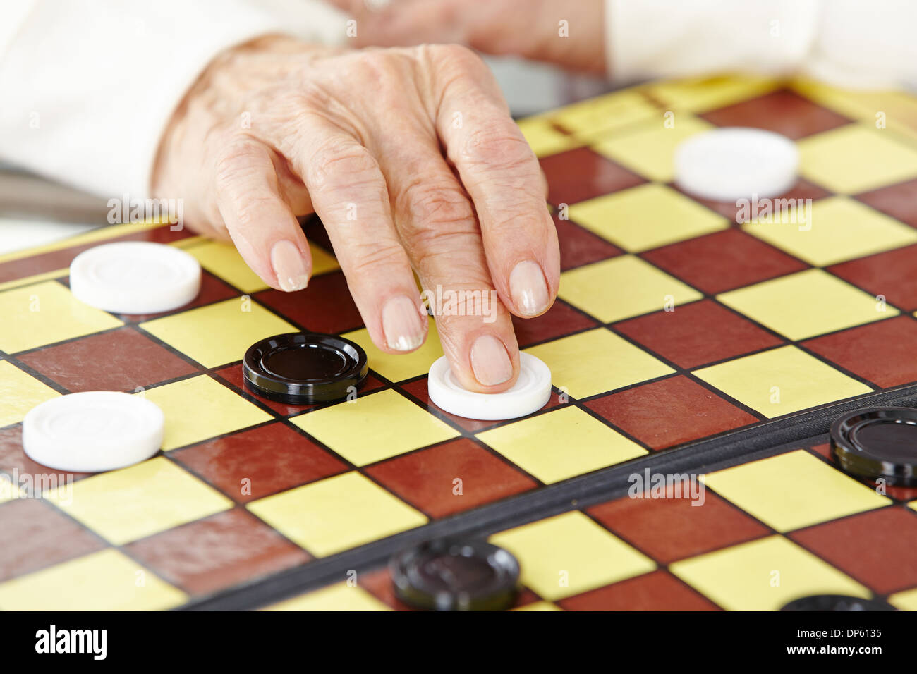 La main ridée d'un senior woman playing checkers Banque D'Images