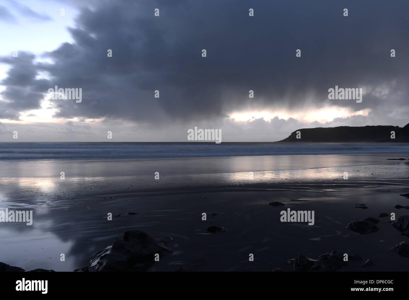 La pluie commence à tomber de sombres nuages reflétée sur la plage Banque D'Images