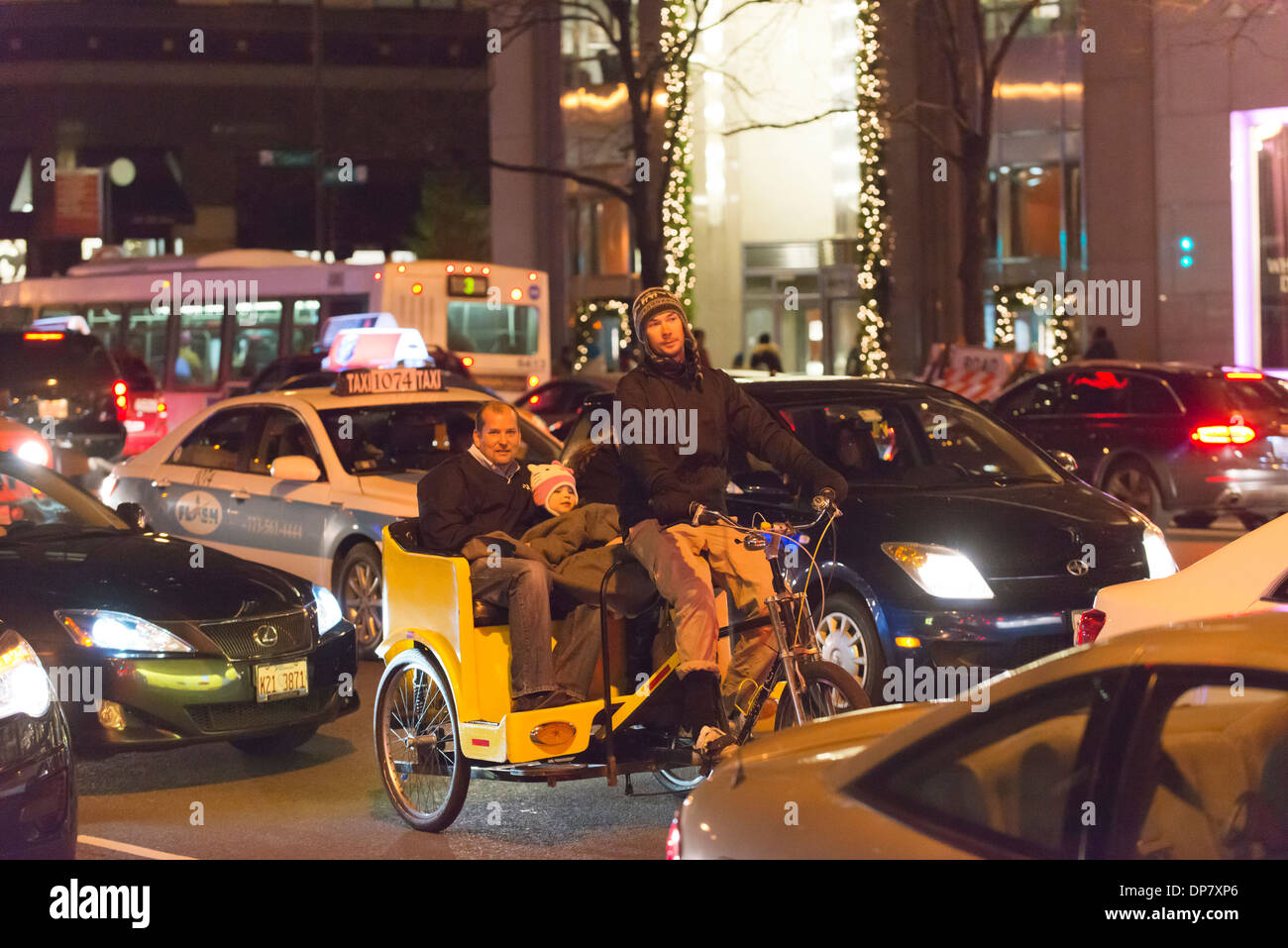 Dans la famille cyclo coincé dans le trafic sur Michigan Avenue la nuit pendant Noël. Banque D'Images