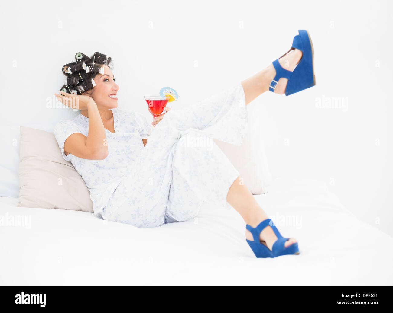 Brunette in hair rollers et wedge shoes holding a cocktail Banque D'Images