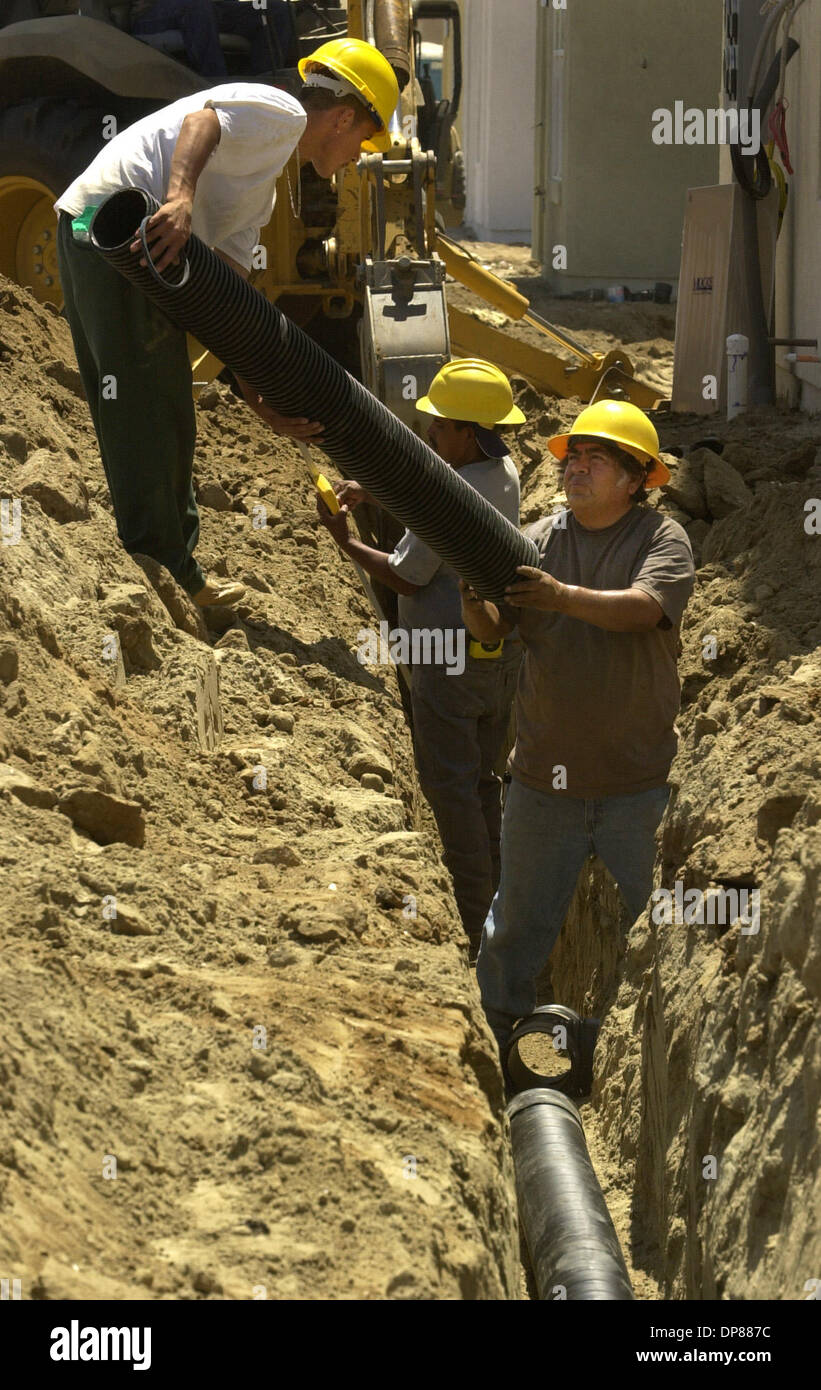 (Publié le 08/11/2002, B-1) Leonardo Gonzalez mains un tuyau vers le bas pour Leon Dominguez cette semaine où la construction de 500 nouveaux logements sont en construction. Peggy Peattie photo. (Correction Publié 08/14/2002, B-2 : Photos paru dimanche avec une histoire à propos de l'habitation en construction au Centre de formation de la Marine n'ont pas d'unités résidentielles qui font partie de San Diego. Banque D'Images