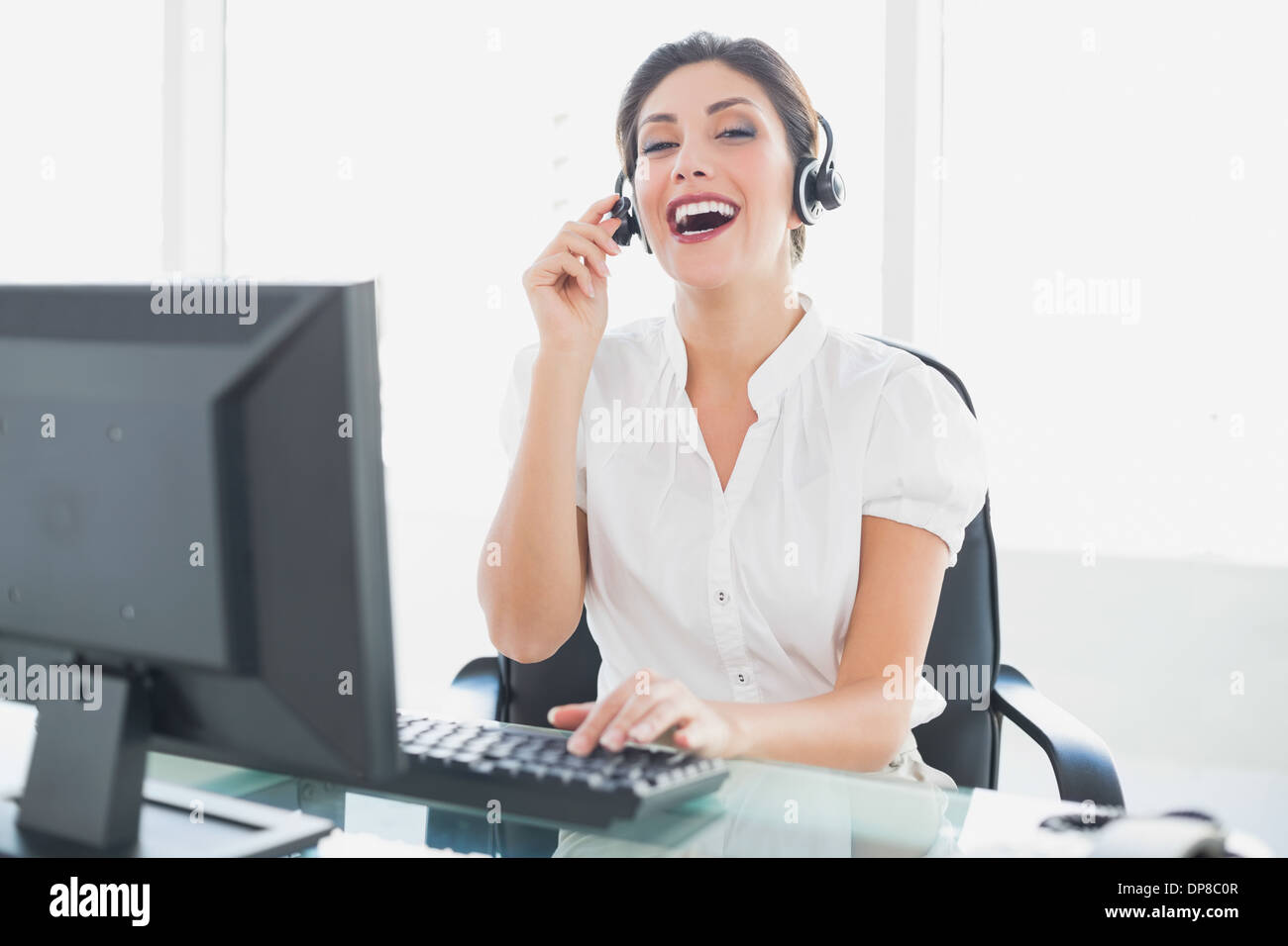 Cheerful call centre agent assise à son bureau sur un appel Banque D'Images