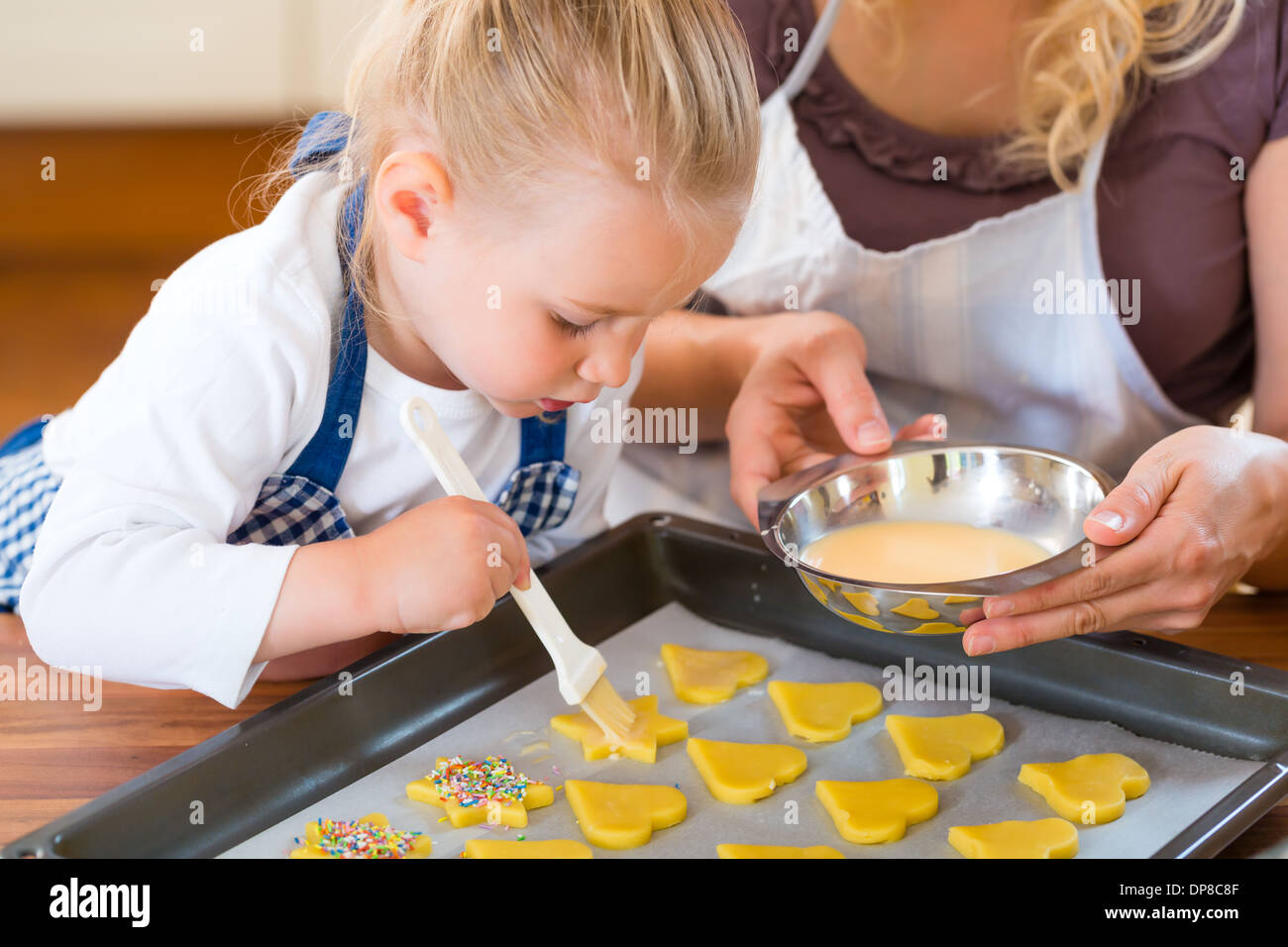 La cuisson avec la famille - Mère et fille coat self made cookies à l'aide d'un pinceau Banque D'Images