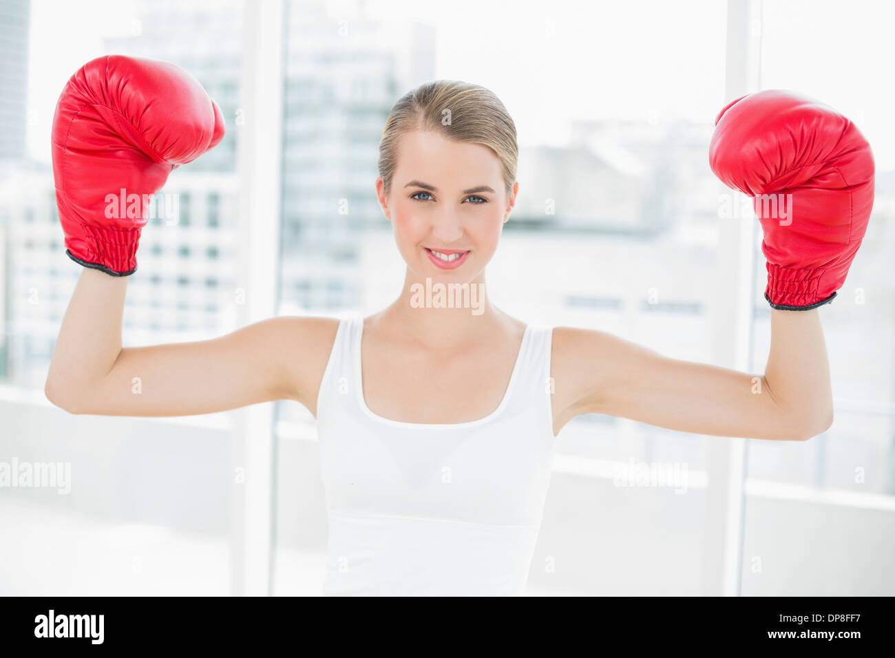 Smiling woman concurrentiel with red boxing gloves cheering up Banque D'Images