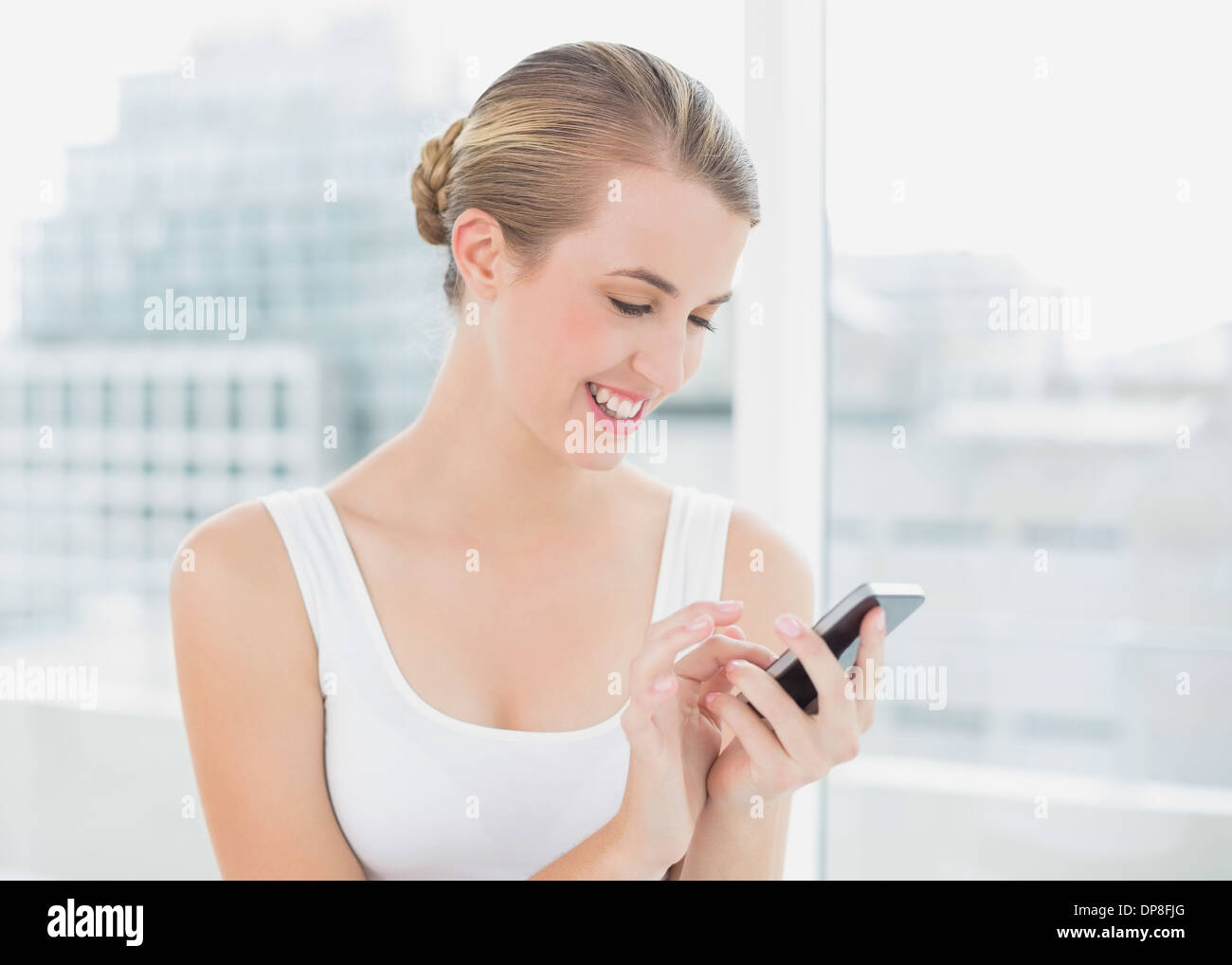 Cheerful blonde woman text messaging Banque D'Images