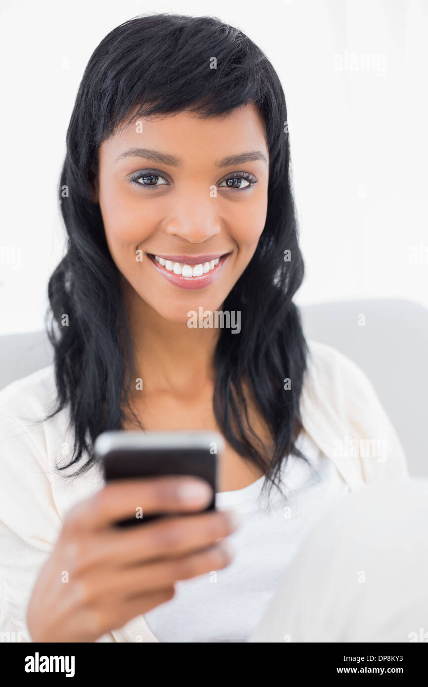Natural black haired woman in white clothes holding a mobile phone Banque D'Images