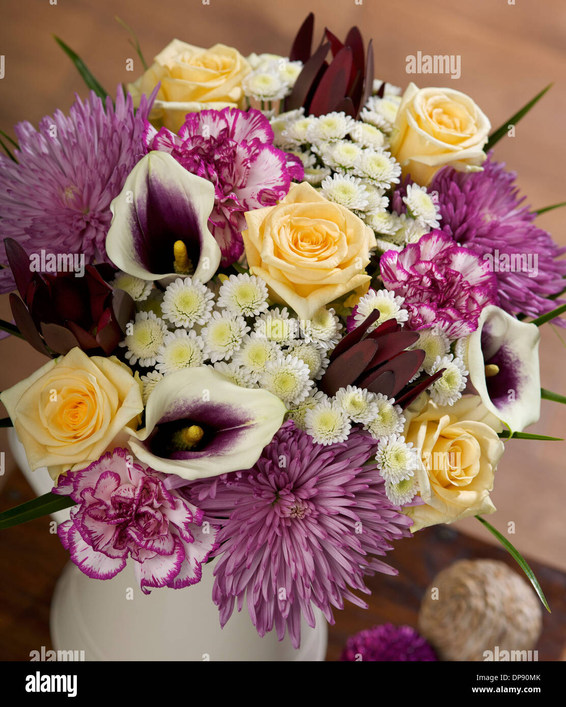 Chrysanthèmes de stalinon blanc, œillets en spray à bords violets, Leucadendron de marron, Lies de Calla pourpres et roses d'avalanche dans un vase dans un cadre familial Banque D'Images