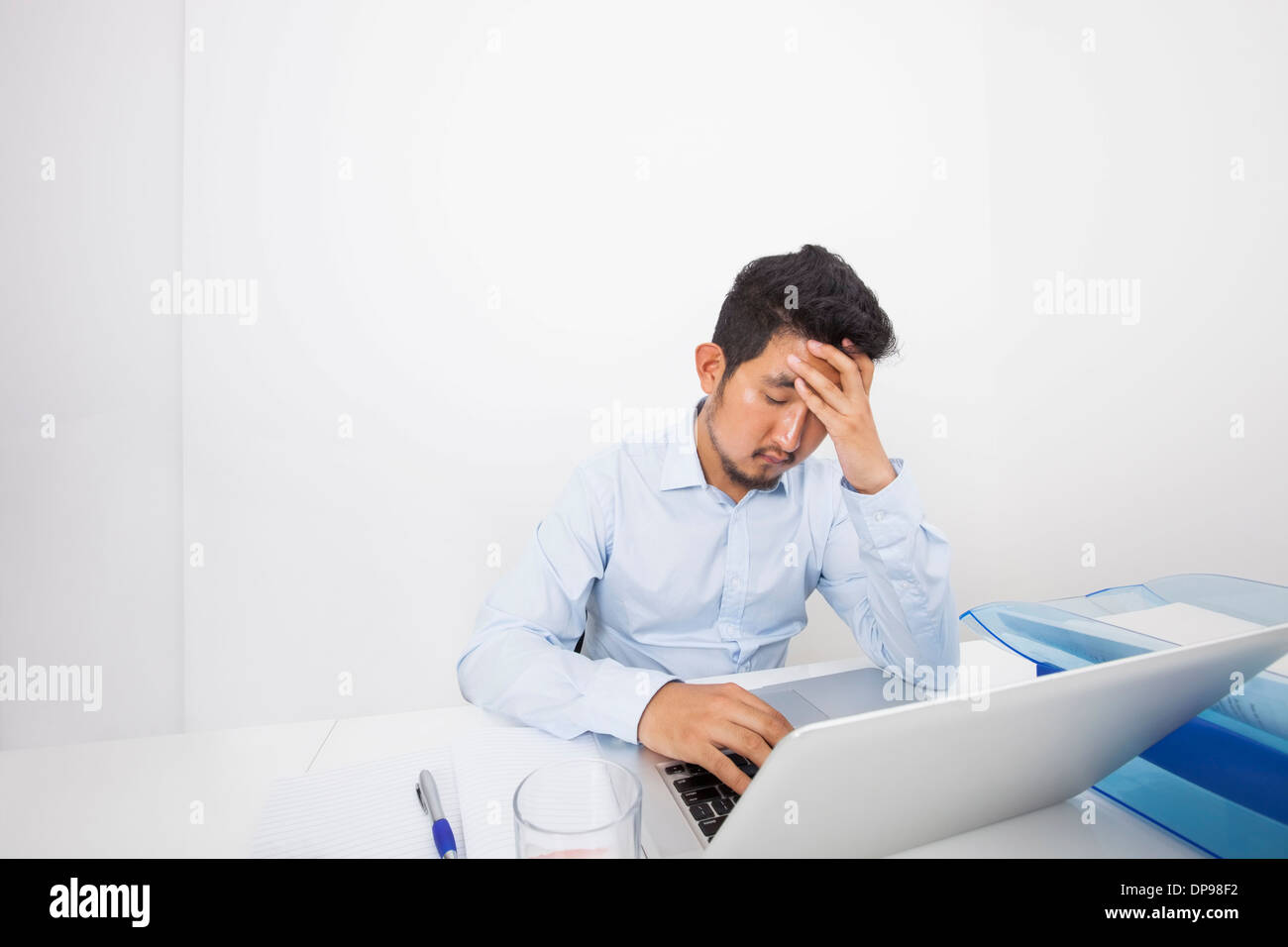Stressed businessman with laptop sitting at desk in office Banque D'Images