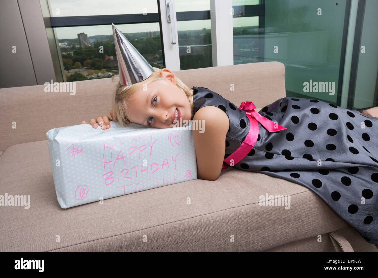 Portrait of Girl with birthday gift lying on sofa at home Banque D'Images
