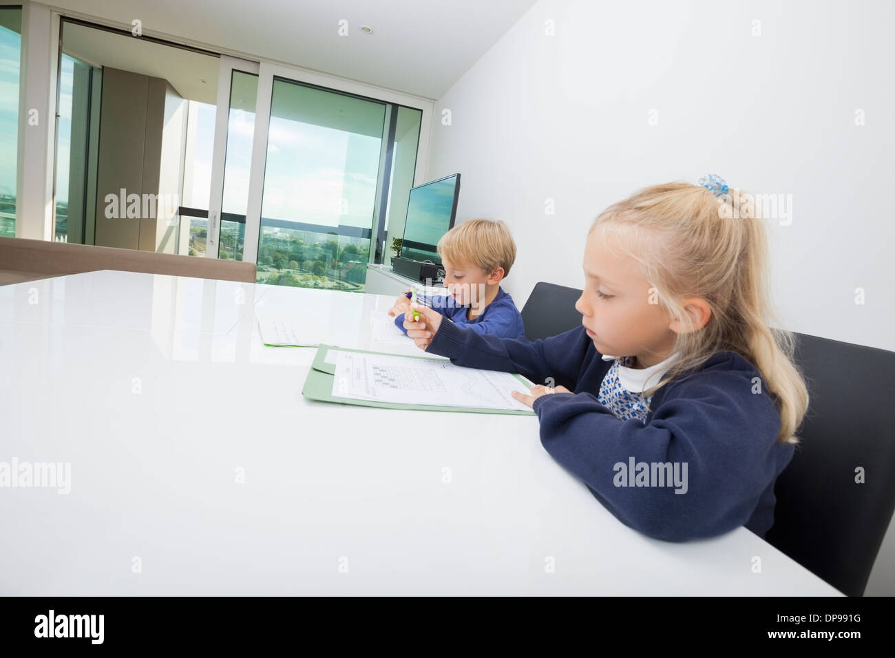 Frères et sœurs à faire leurs devoirs à table dans la maison Banque D'Images