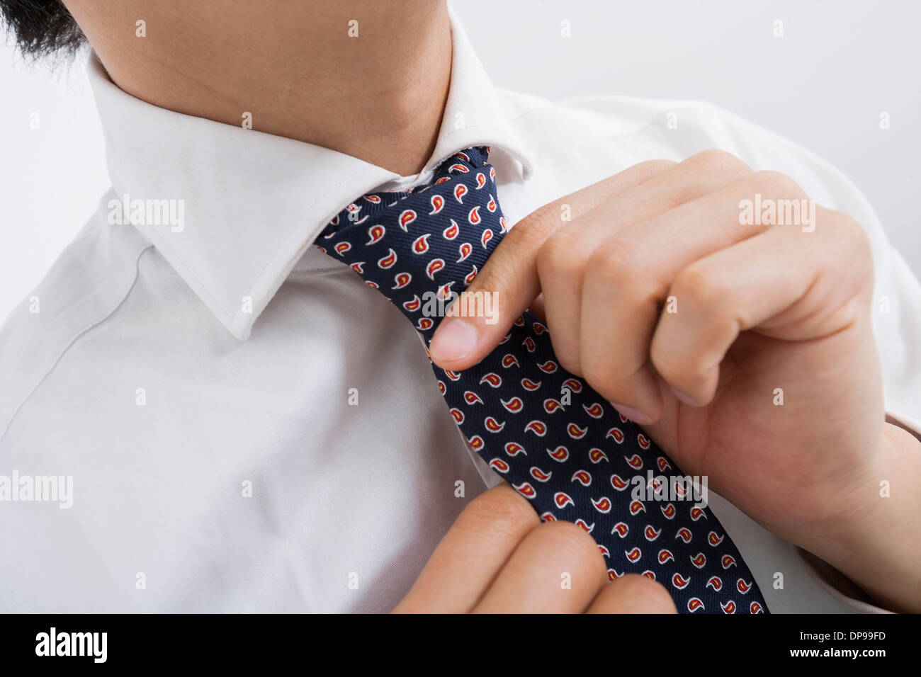 Portrait of Mid adult businessman adjusting tie Banque D'Images