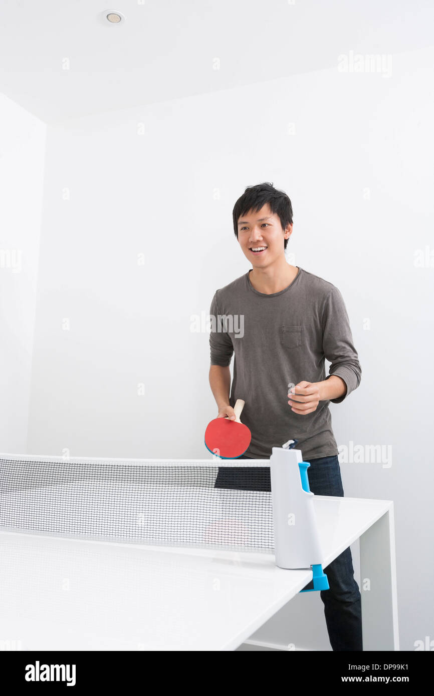 Happy Mid adult man playing ping pong Banque D'Images