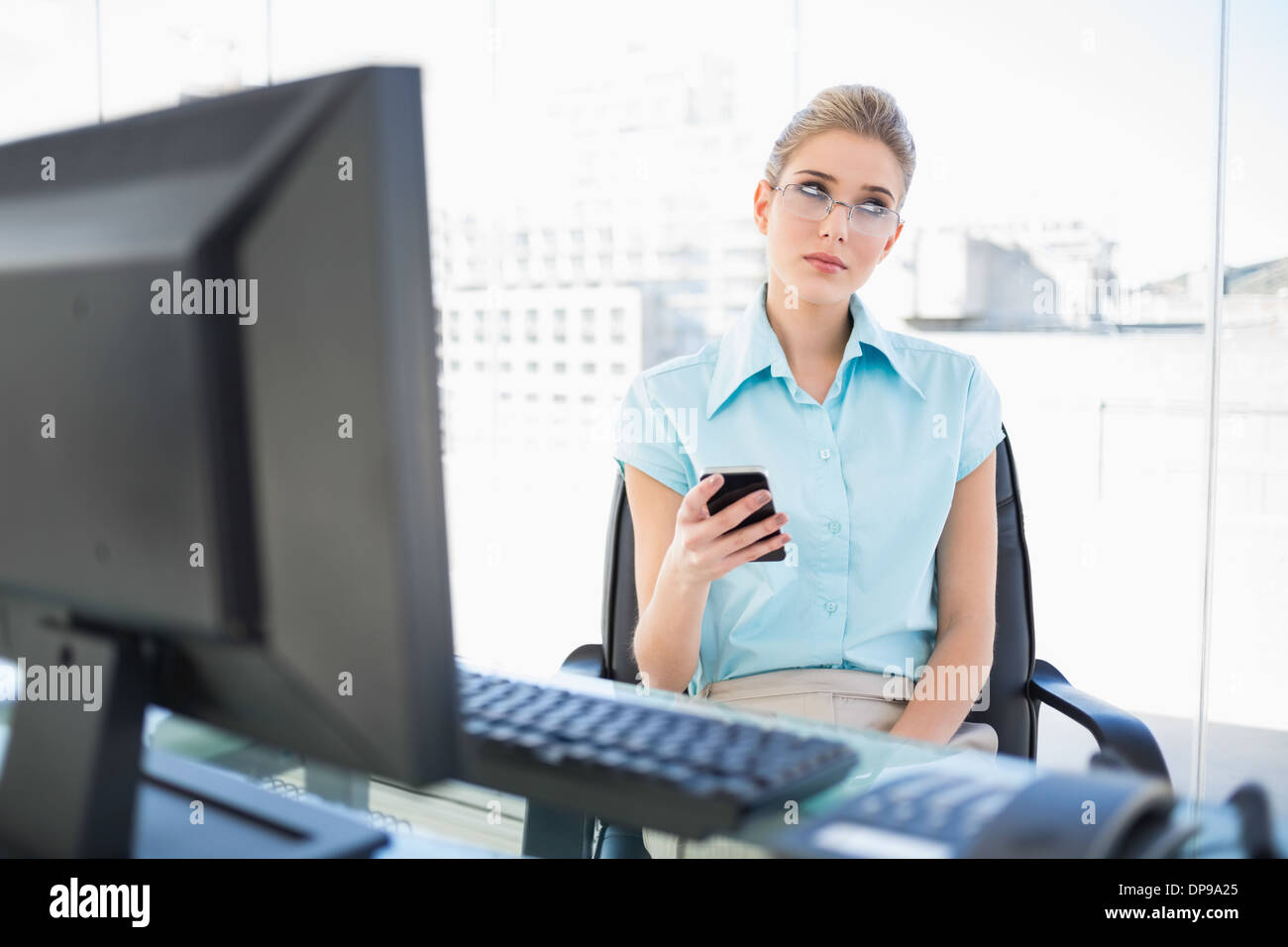 Pensive businesswoman wearing glasses text messaging Banque D'Images