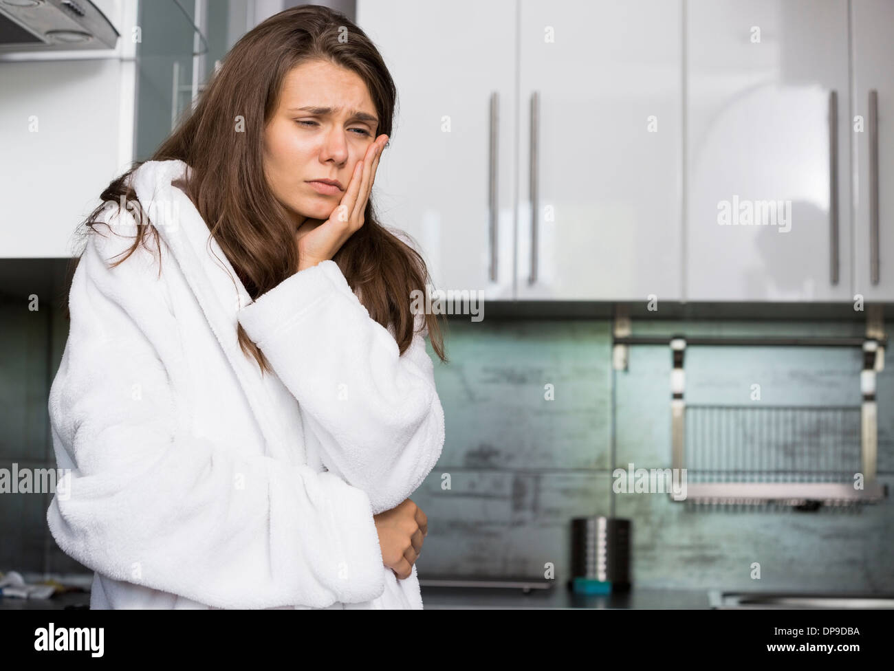 Triste femme souffrant de maux standing in kitchen Banque D'Images