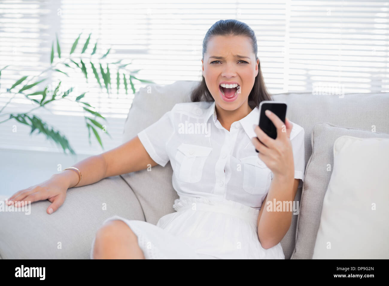 Angry woman holding her phone hurler à huis clos Banque D'Images