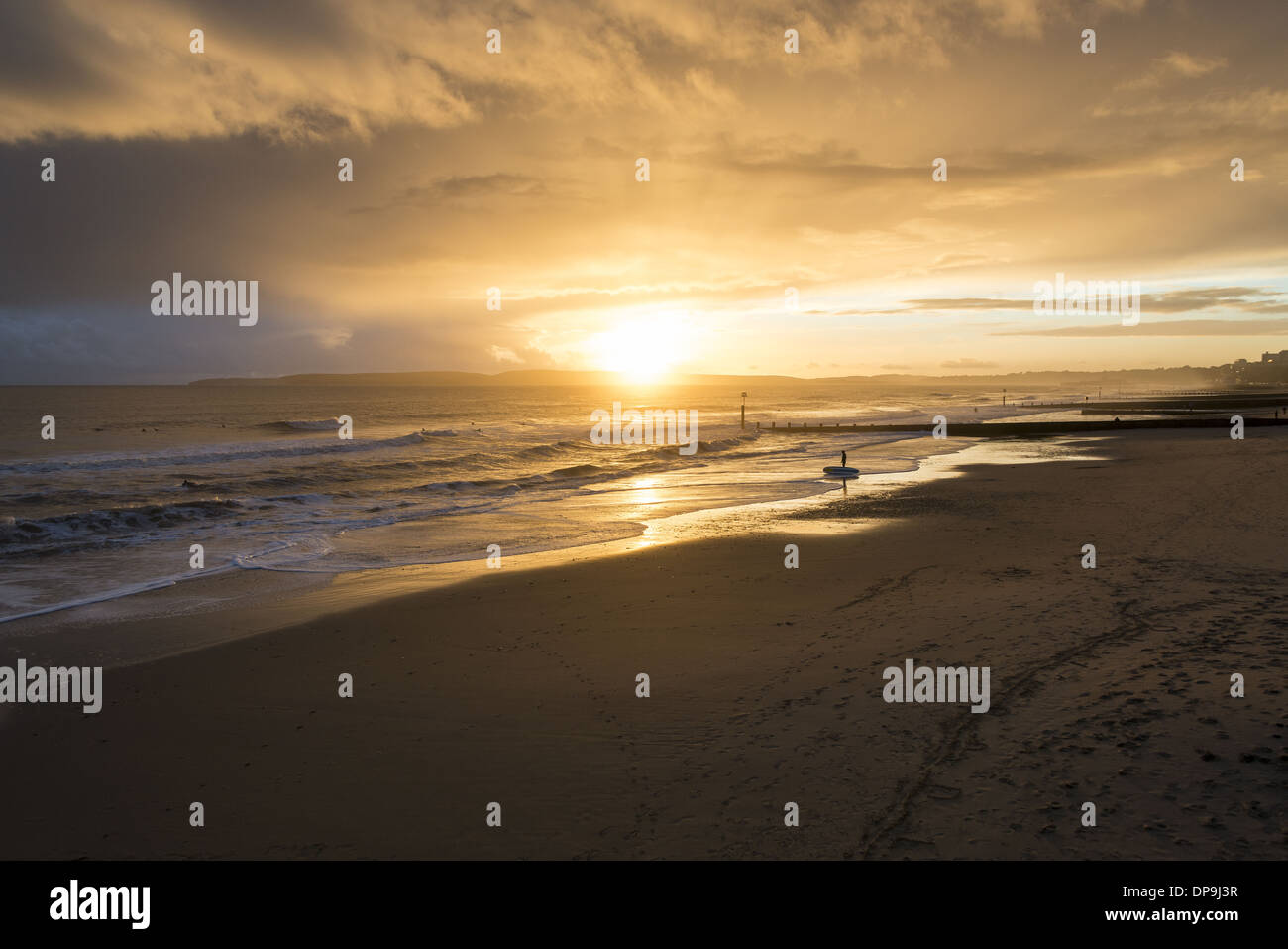 Surfeur debout sur le rivage avec sa planche de surf qui donne sur la mer sur la plage de Boscombe à Dorset, Angleterre, Royaume-Uni Banque D'Images