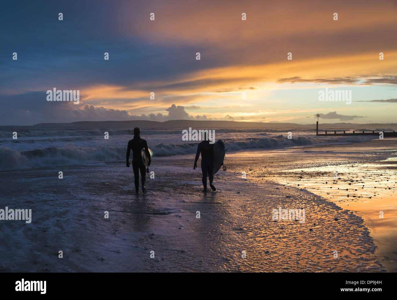 Balades le long du littoral des surfeurs au coucher du soleil sur la plage de Boscombe dans le Dorset, Angleterre, RU Banque D'Images