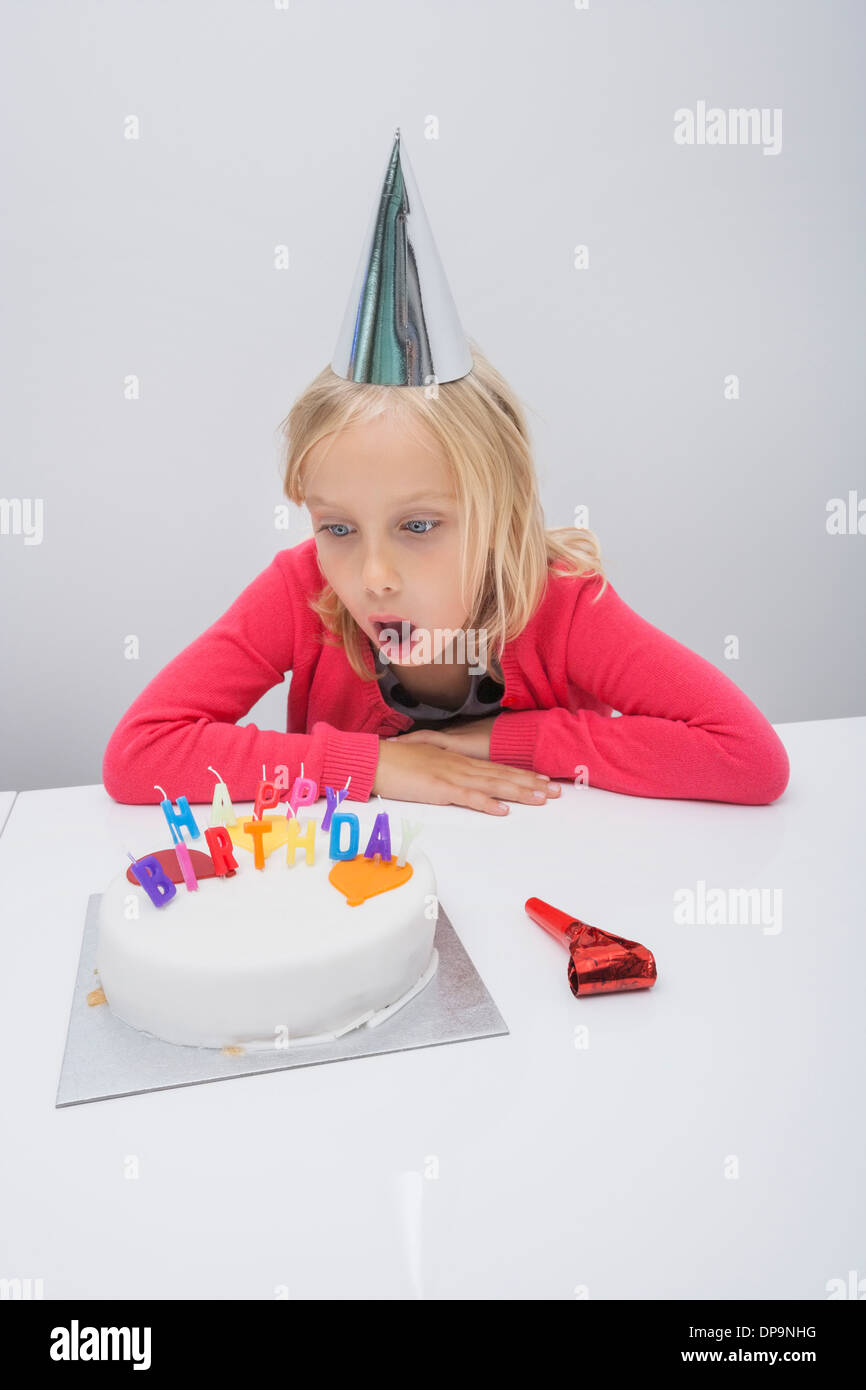 Surpris girl looking at birthday cake on table in house Banque D'Images
