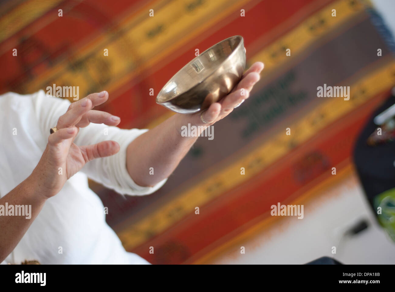 Un bol chantant tibétain dans les mains d'un thérapeute Banque D'Images