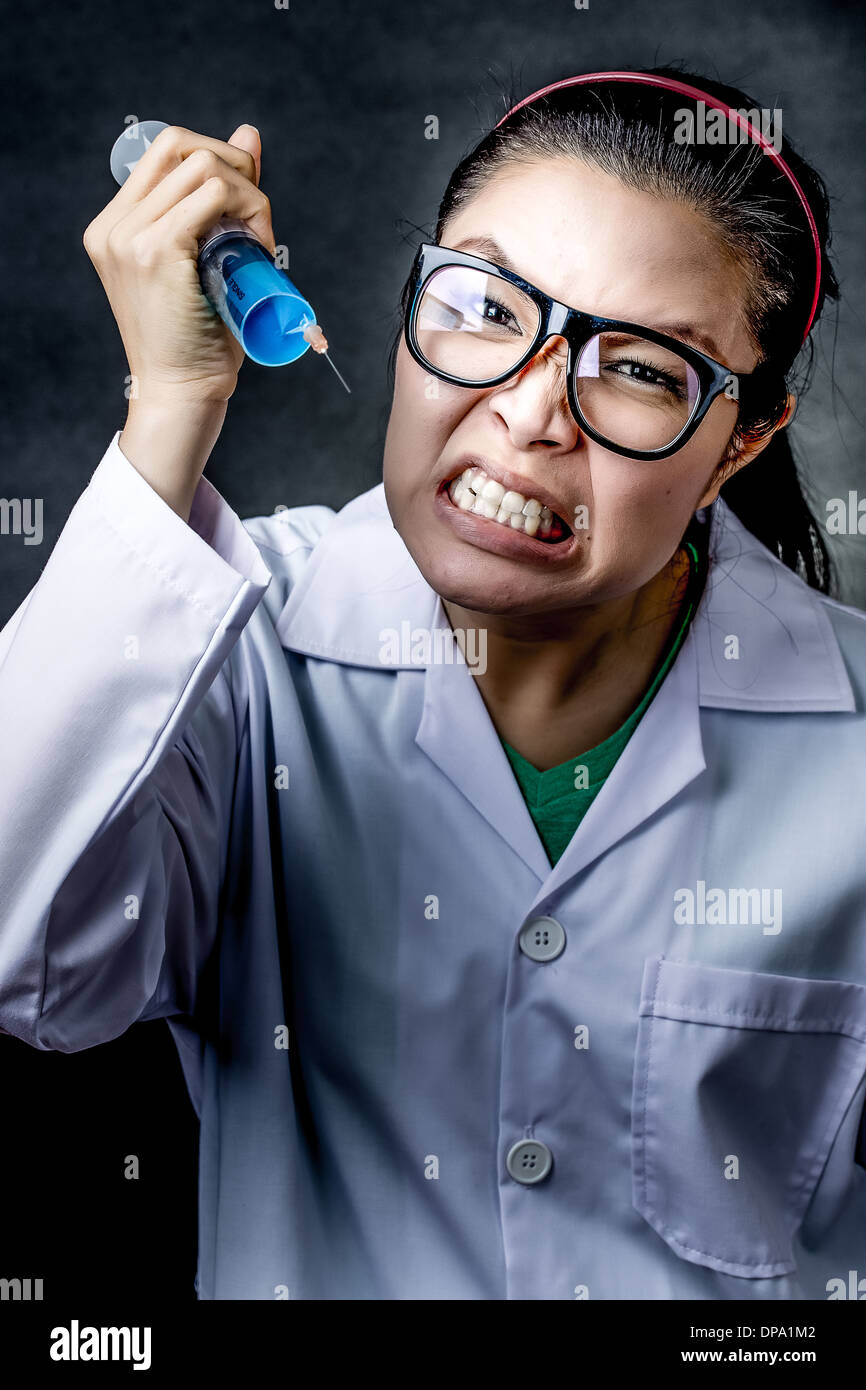 Fou de colère médecin asiatique avec une seringue le tournage en studio Banque D'Images