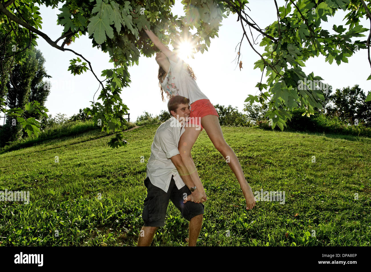 Jeune homme jeune femme de levage pour les branches d'arbres Banque D'Images