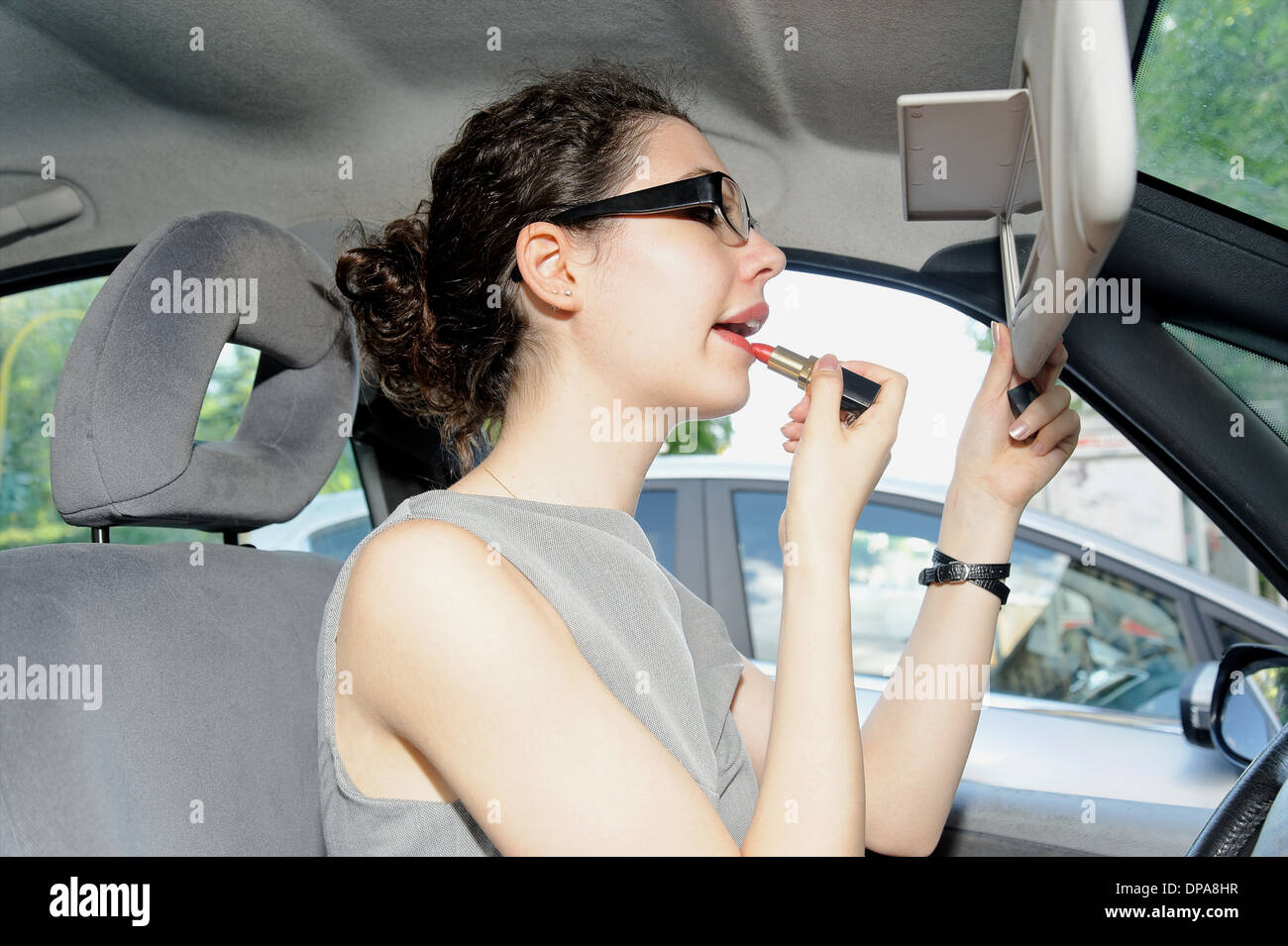 Young woman applying lipstick in car Banque D'Images