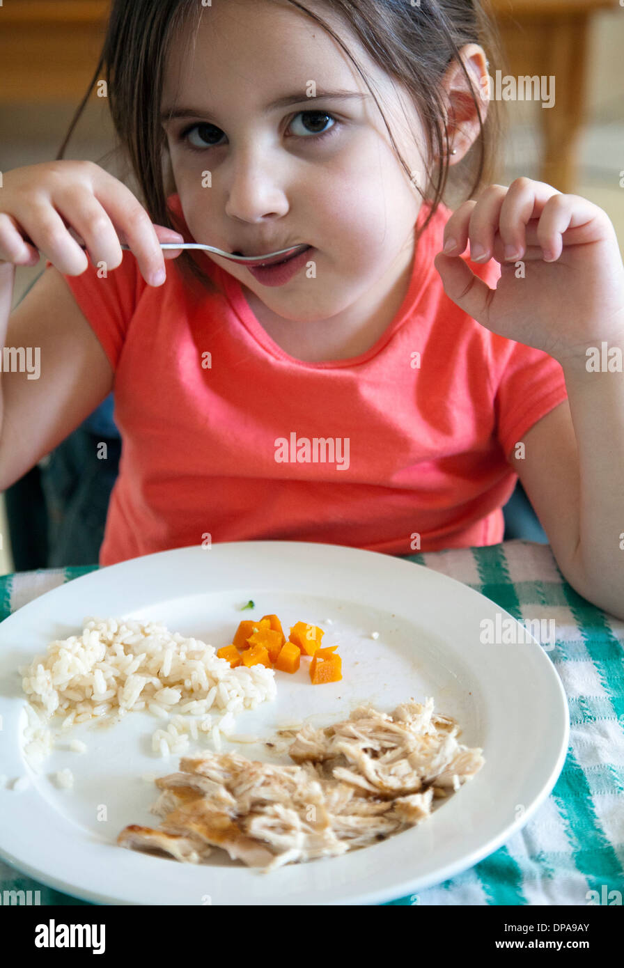 Young Girl Eating Dinner at Table Banque D'Images