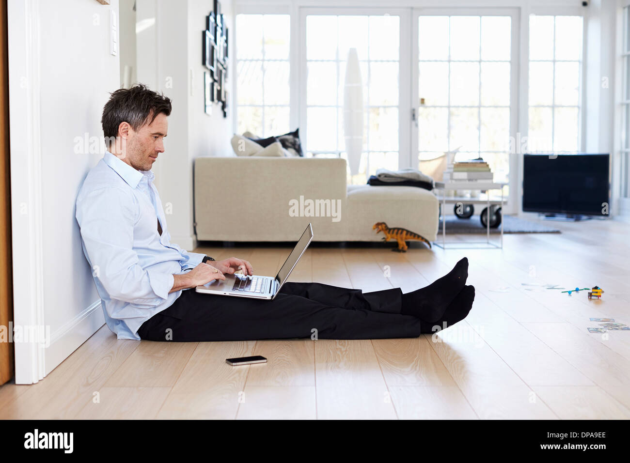 Man sitting on floor using laptop Banque D'Images