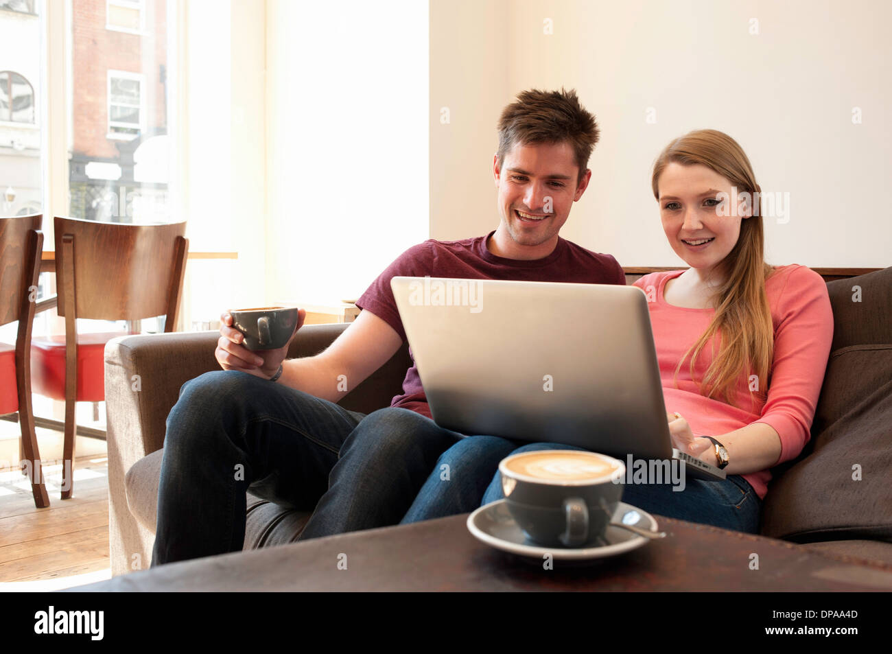 Jeune couple à la recherche à l'ordinateur personnel dans cafe Banque D'Images