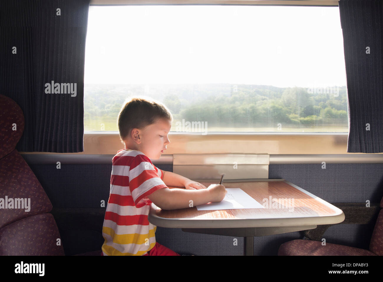 Jeune garçon avec un crayon et du papier sur le train Banque D'Images