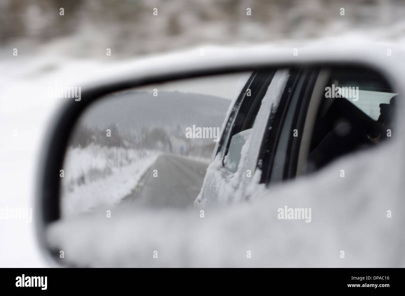 Collines couvertes de neige et de la route dans le rétroviseur d'une voiture Banque D'Images