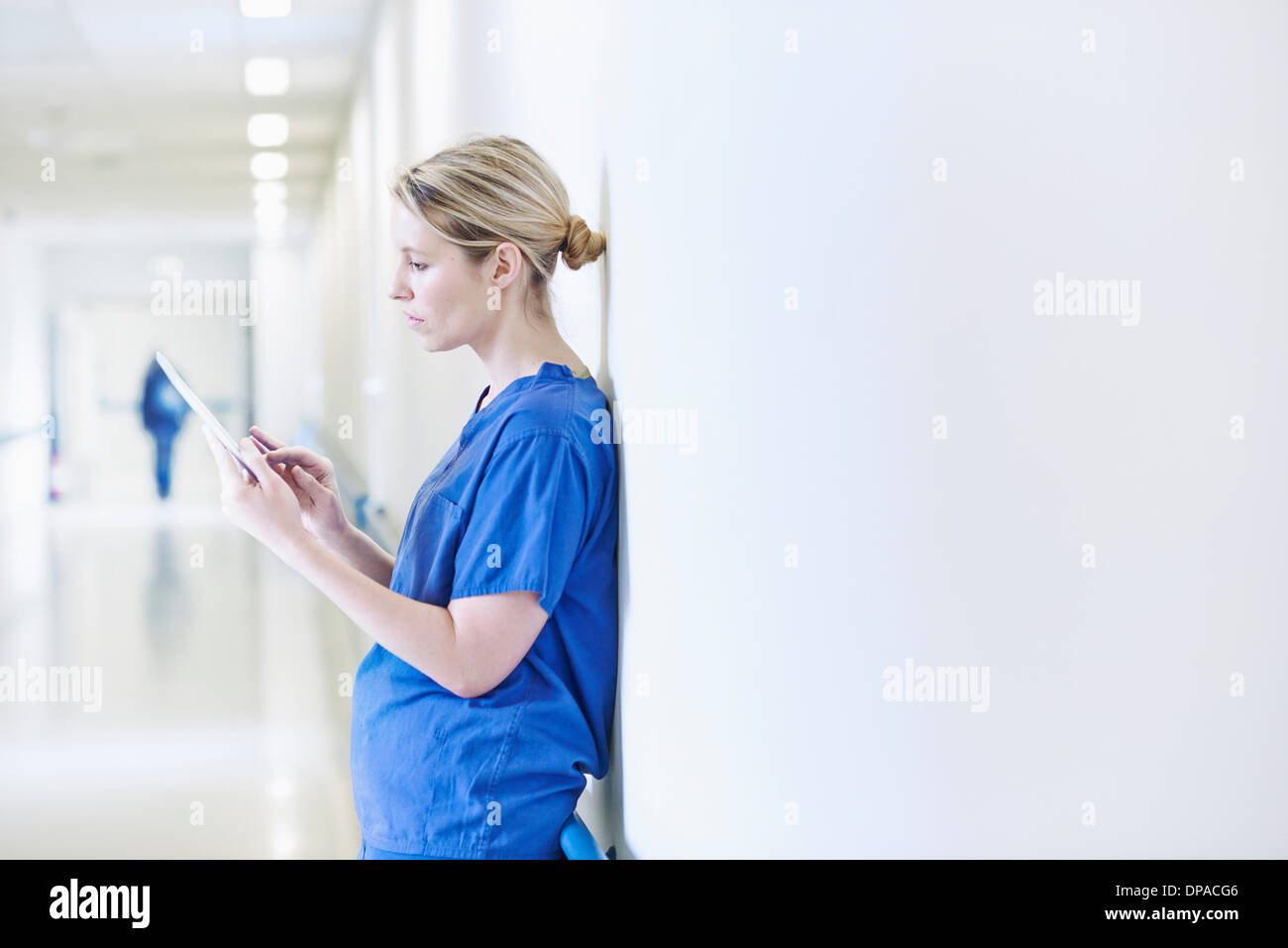 Doctor standing in corridor looking at digital tablet Banque D'Images