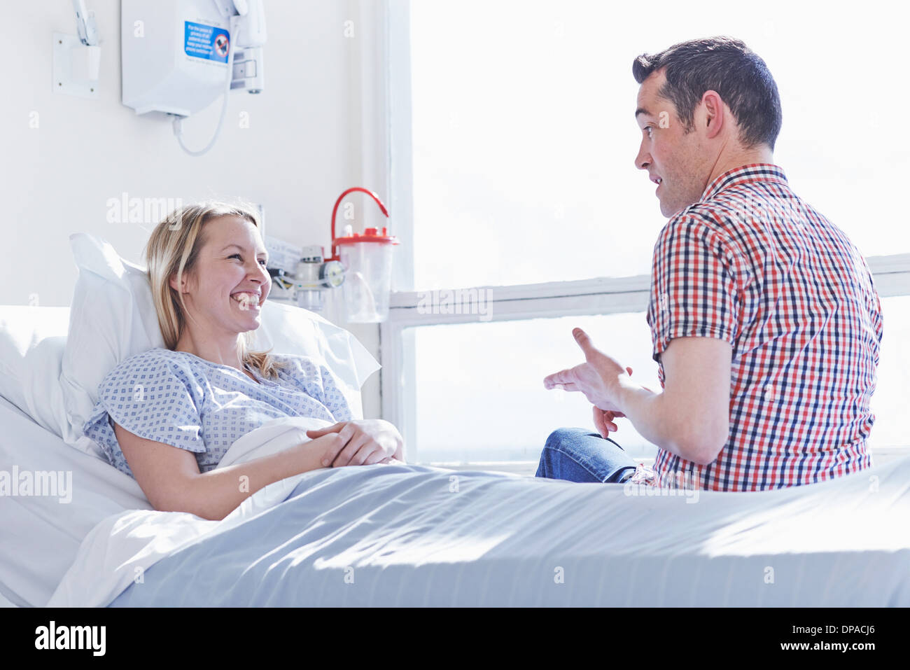Patient lying in hospital bed parler aux visiteur Banque D'Images