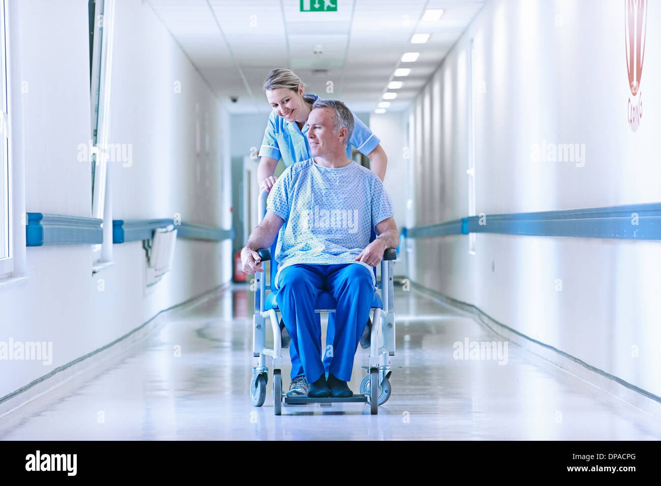 Nurse pushing patient in wheelchair down corridor Banque D'Images