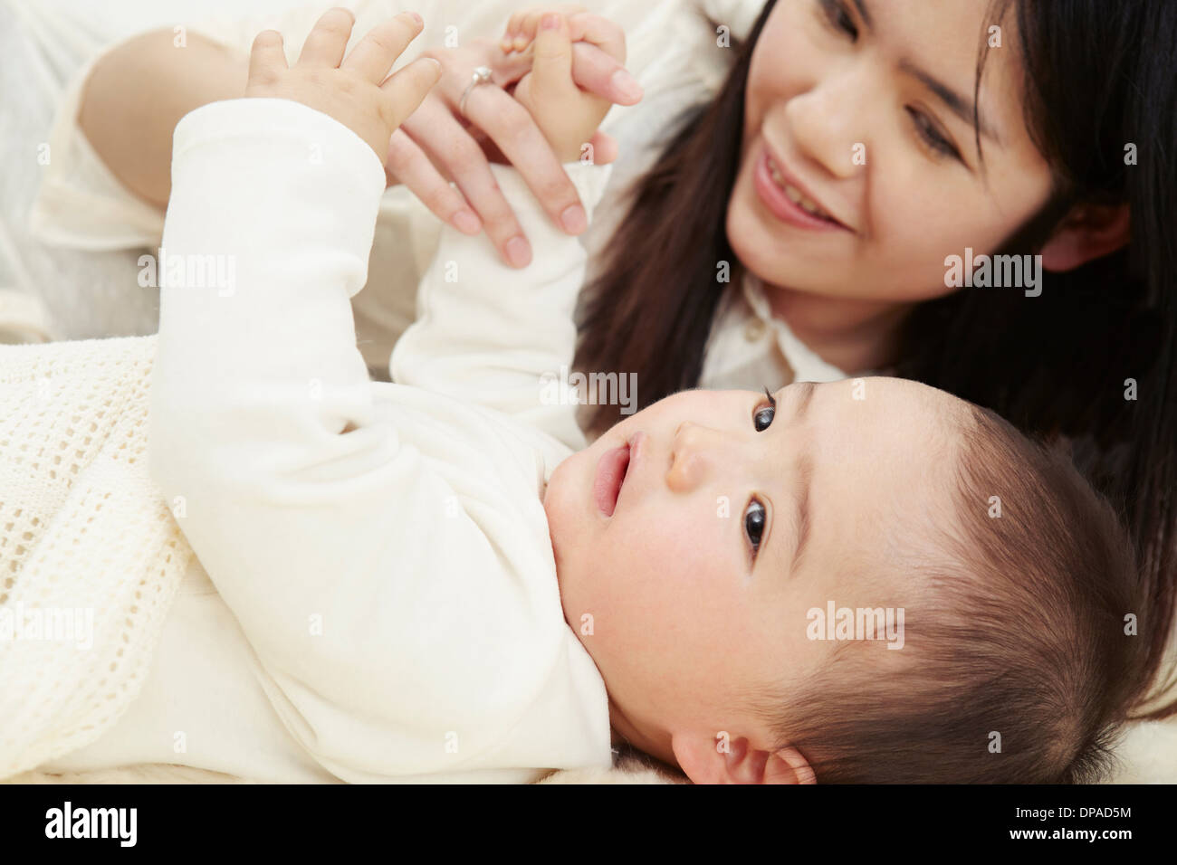 Mère et bébé boy lying together holding hands Banque D'Images