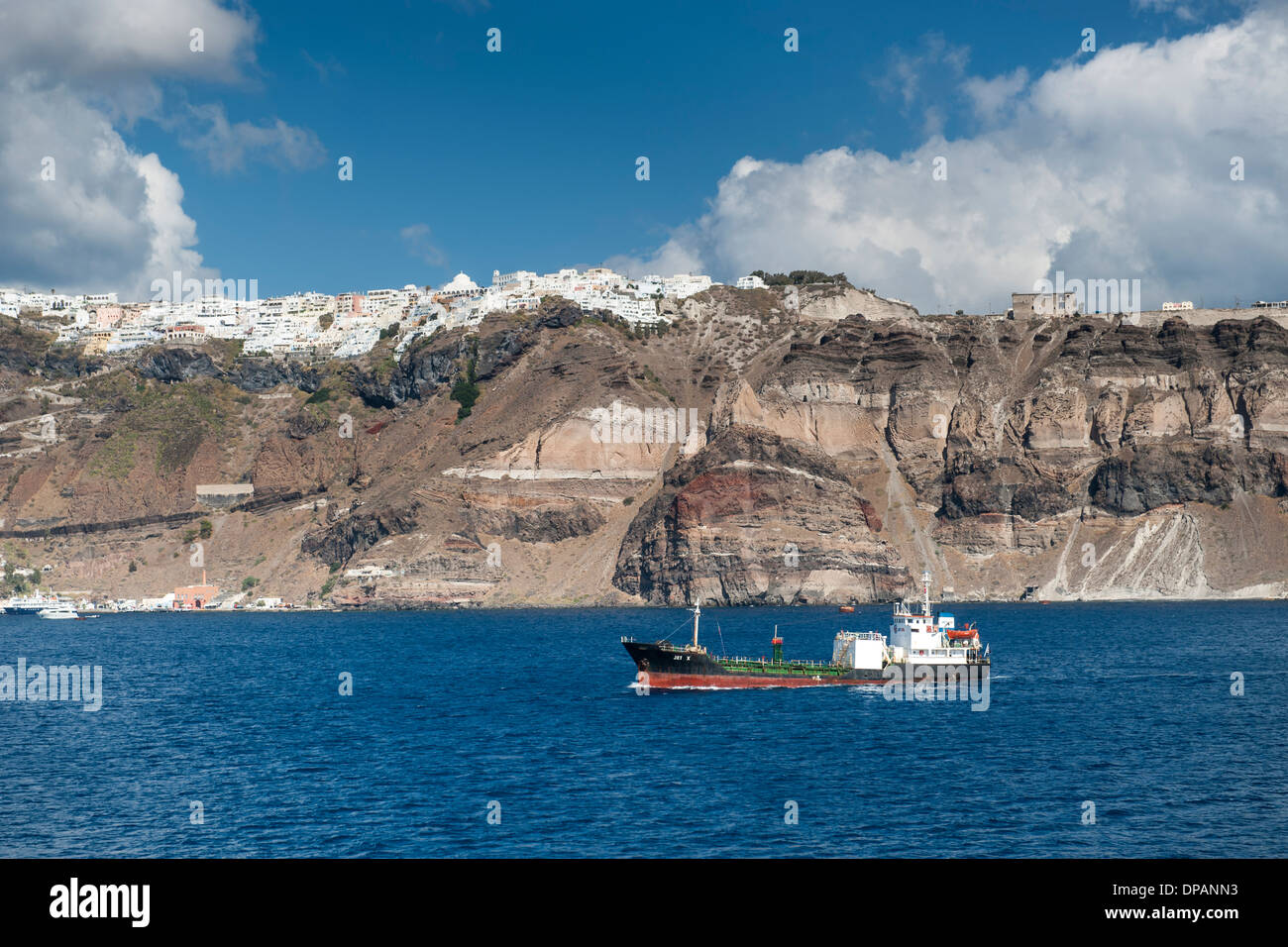 Vue du village de Fira et à un bateau naviguant au large de la côte de l'île grecque de Santorin. Banque D'Images
