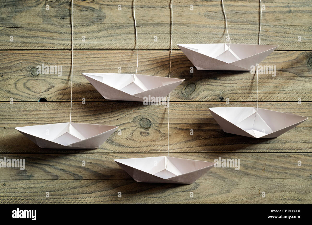 Ficelle papier bateaux pendaison sur fond de bois Banque D'Images