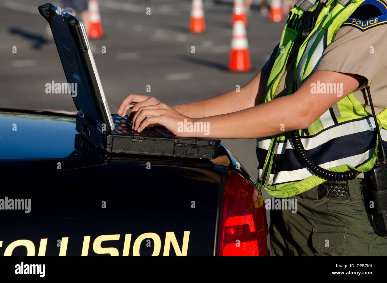 Une agente de police les types sur son ordinateur portable pendant un appel. Banque D'Images