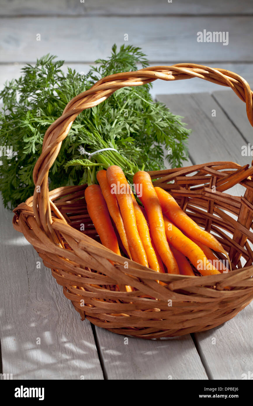 Botte de carottes dans le panier sur la table en bois Banque D'Images