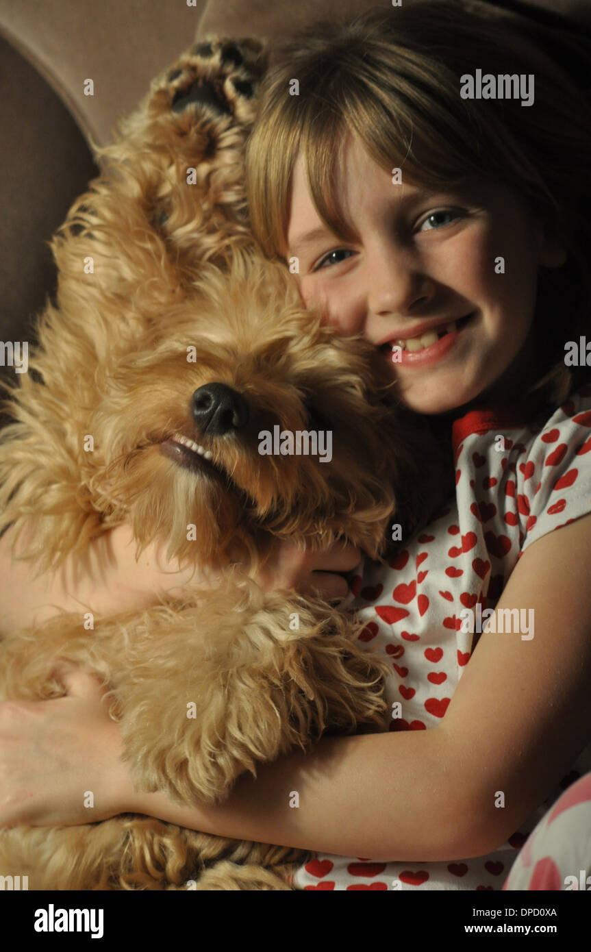 Petite fille sourit comme elle câline son sourire puppy dog Banque D'Images