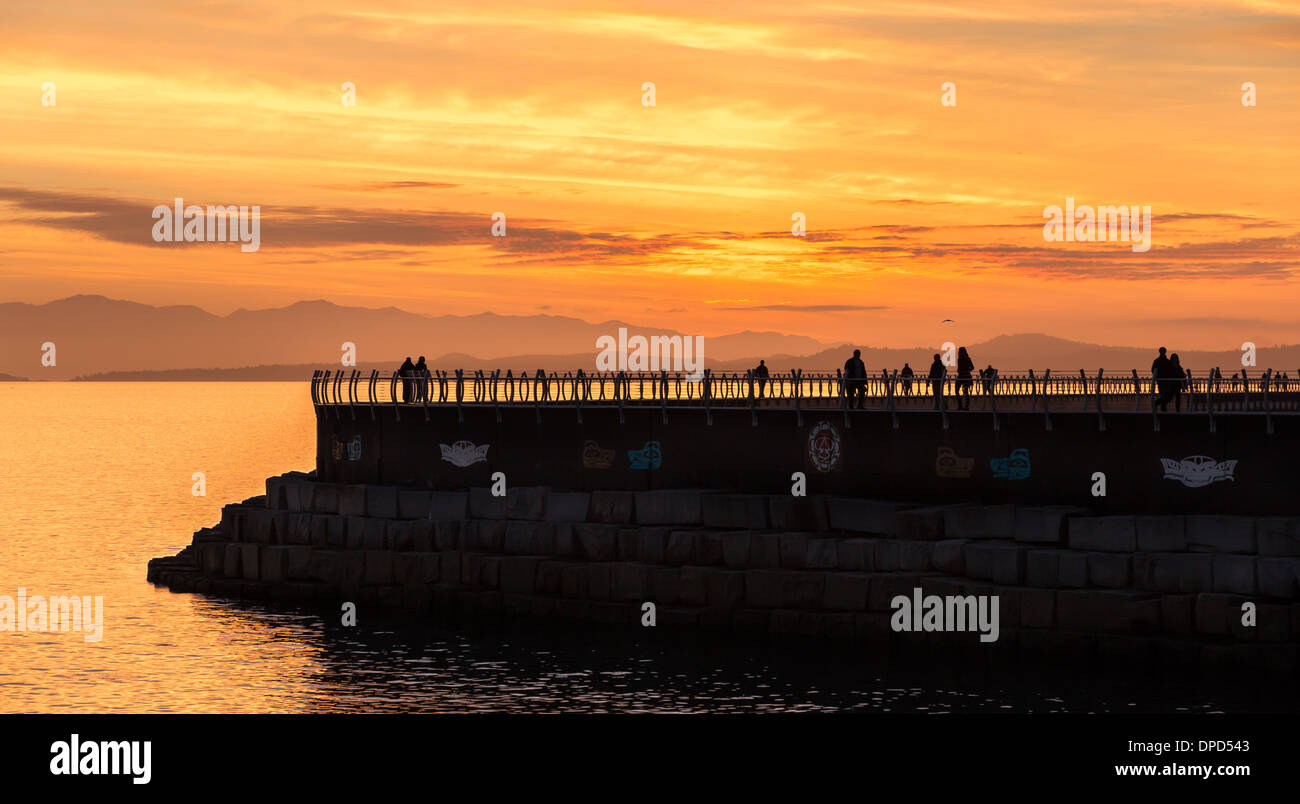 Les gens pour une promenade du soir profiter d'un magnifique coucher de soleil sur un brise-lames à Victoria, Colombie-Britannique, Canada Banque D'Images