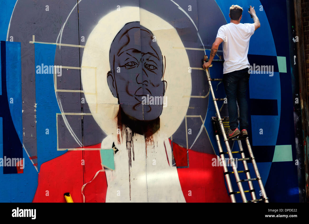 L'homme sur l'échelle la peinture par pulvérisation graffiti street art urbain dans la région de Brick Lane, East London E1 UK Banque D'Images