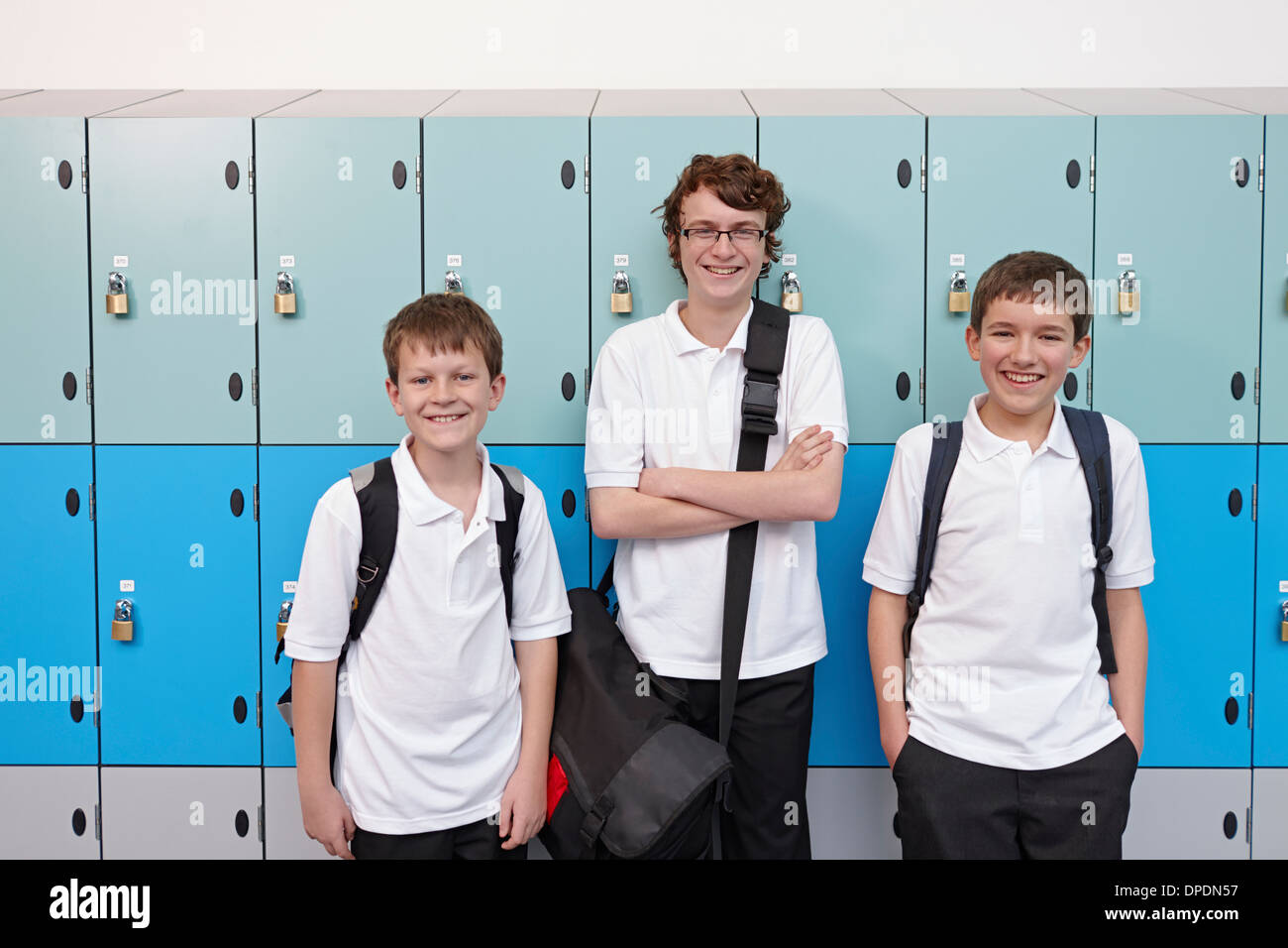 Portrait de trois garçons à côté des casiers de l'école Banque D'Images