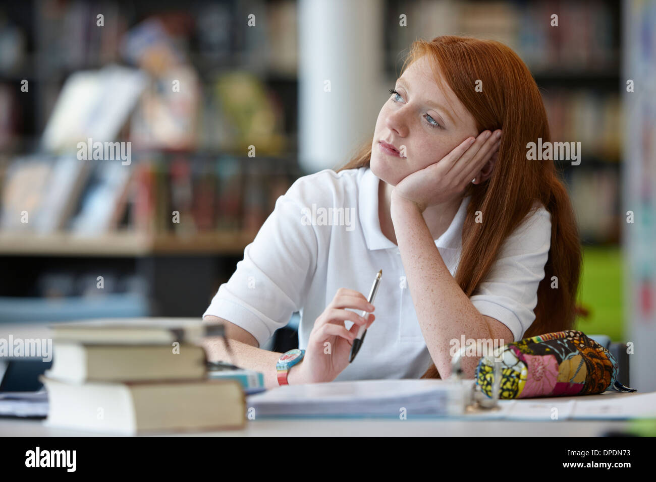 Portrait of teenage girl daydreaming in library Banque D'Images