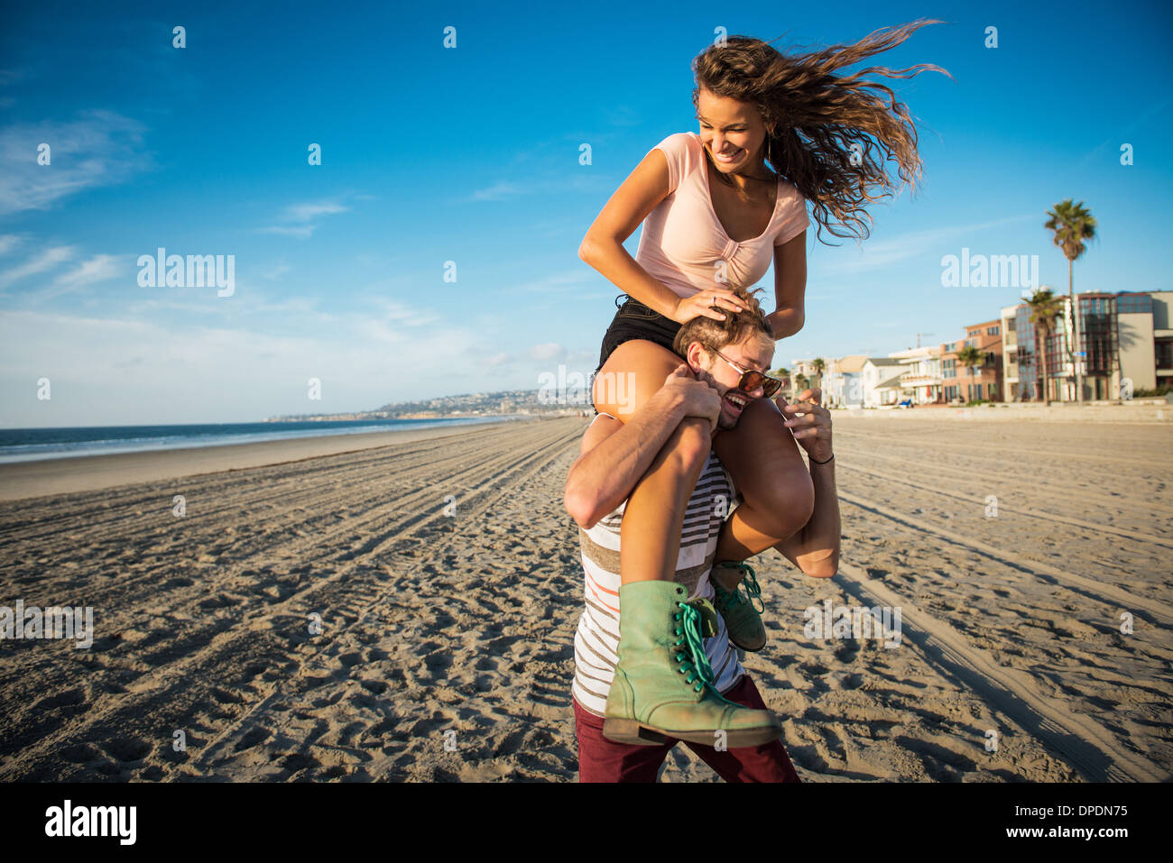 Young man carrying girlfriend sur vos épaules sur San Diego beach Banque D'Images