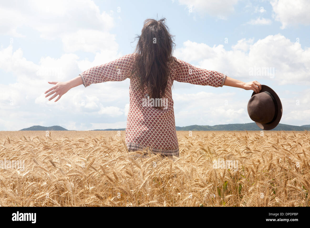 Mid adult woman standing in wheat field with arms out large Banque D'Images
