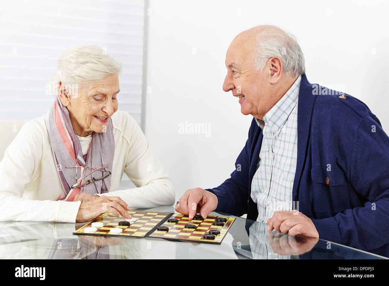 Happy senior couple jouer aux dames ensemble dans une maison de retraite Banque D'Images