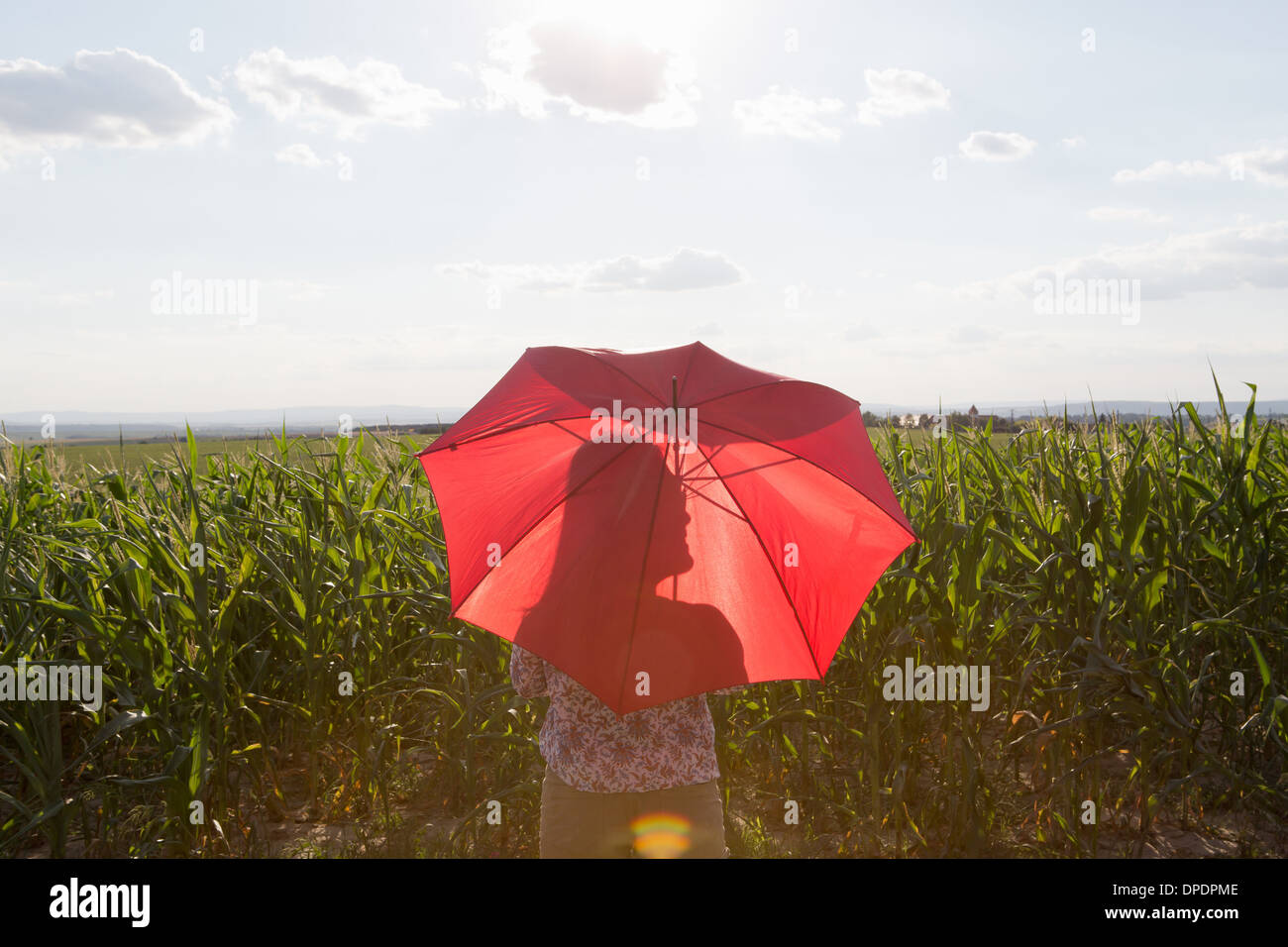 Femme debout tenant parapluie rouge Banque D'Images