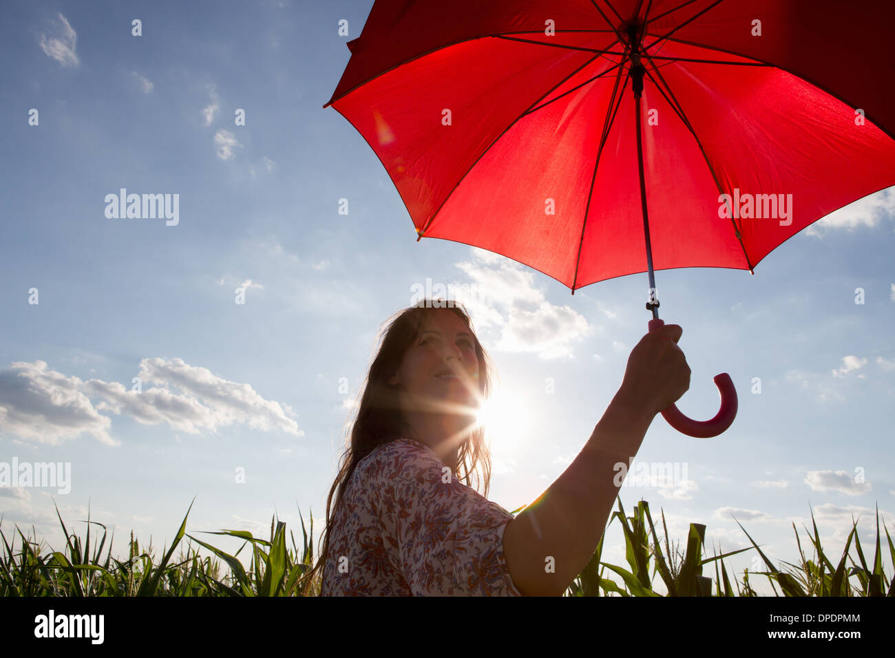 Femme debout tenant parapluie rouge Banque D'Images