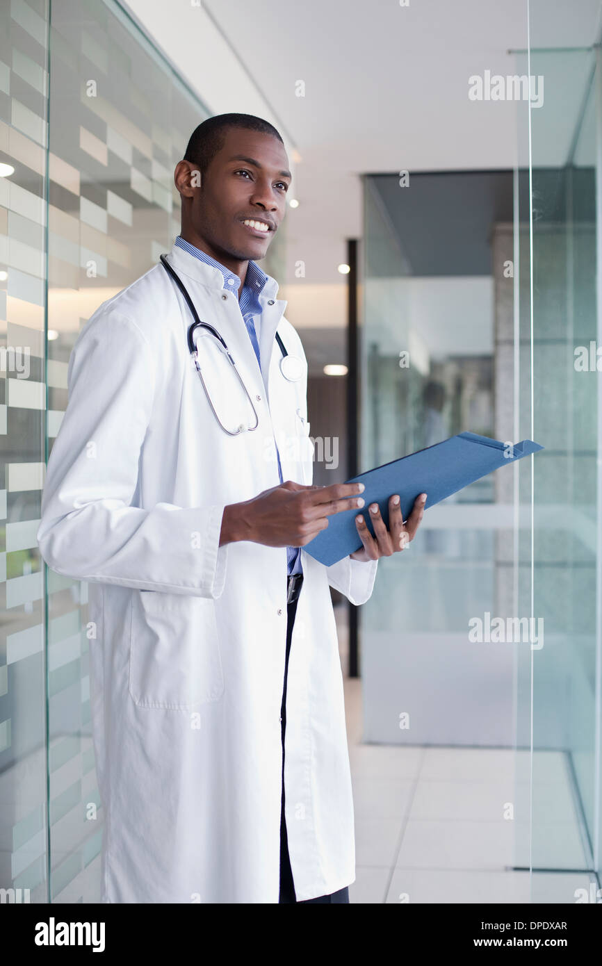 Doctor standing in hospital corridor holding paperwork Banque D'Images